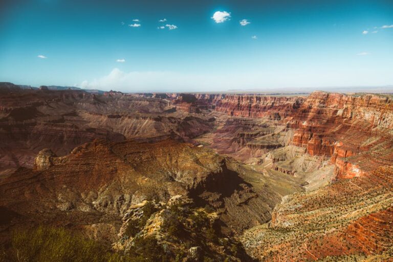 Paisaje del Gran Cañón con impresionantes formaciones rocosas y un cielo despejado. Los tonos cálidos de la tierra resaltan las capas geológicas del cañón. Ideal para amantes de la naturaleza y la fotografía.