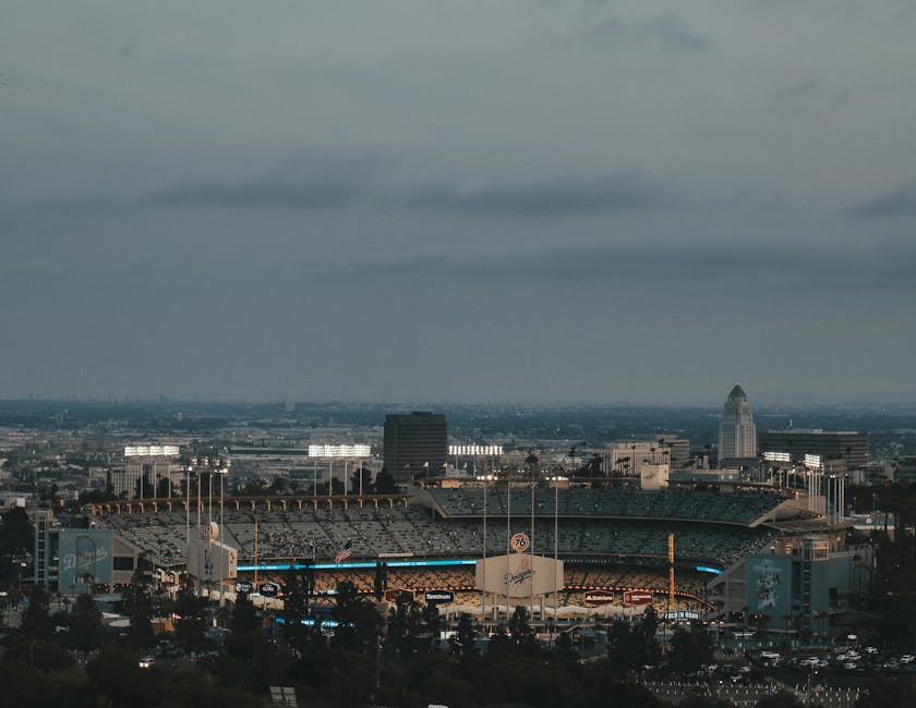 Vista panorámica del estadio bajo un cielo nublado, con luces brillantes en un ambiente urbano.