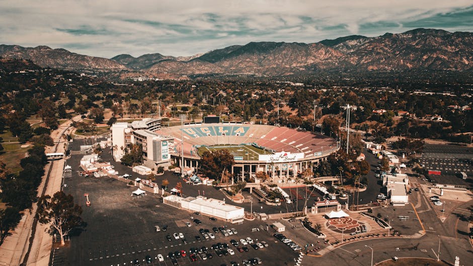 Estadio Rose Bowl de UCLA rodeado de montañas y naturaleza en una vista aérea.